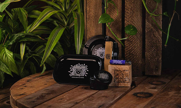 Medusafilters Zubehoer wie Aschenbecher, Rolling Tray, Grinder aufgereiht auf Holz
